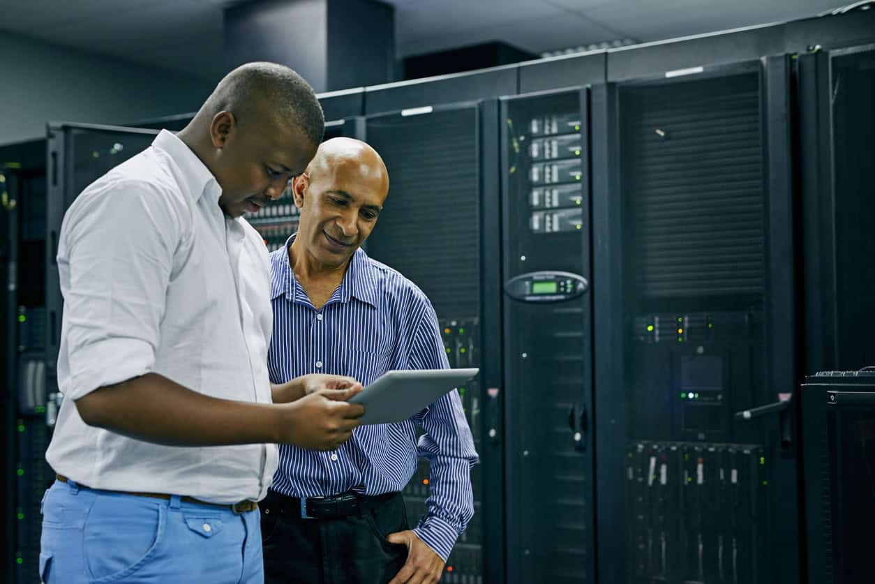 Shot of two IT technicians using a digital tablet while working in a data center
