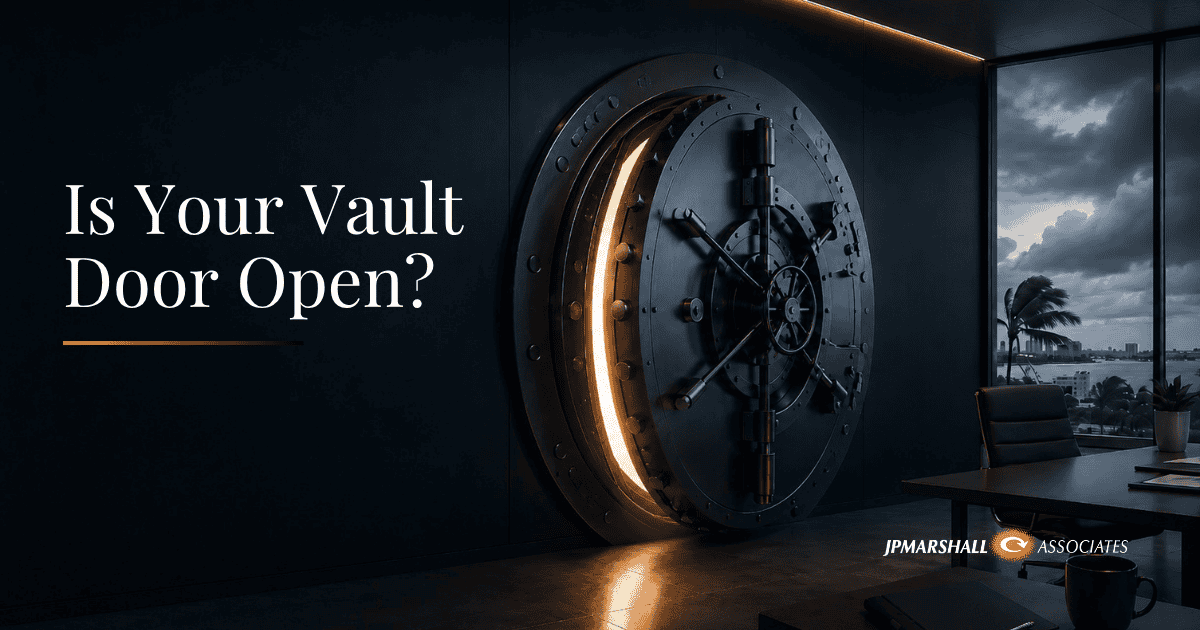 Large bank vault door partially open in a modern office with storm clouds visible outside, symbolizing hidden cybersecurity risks during hurricane season.